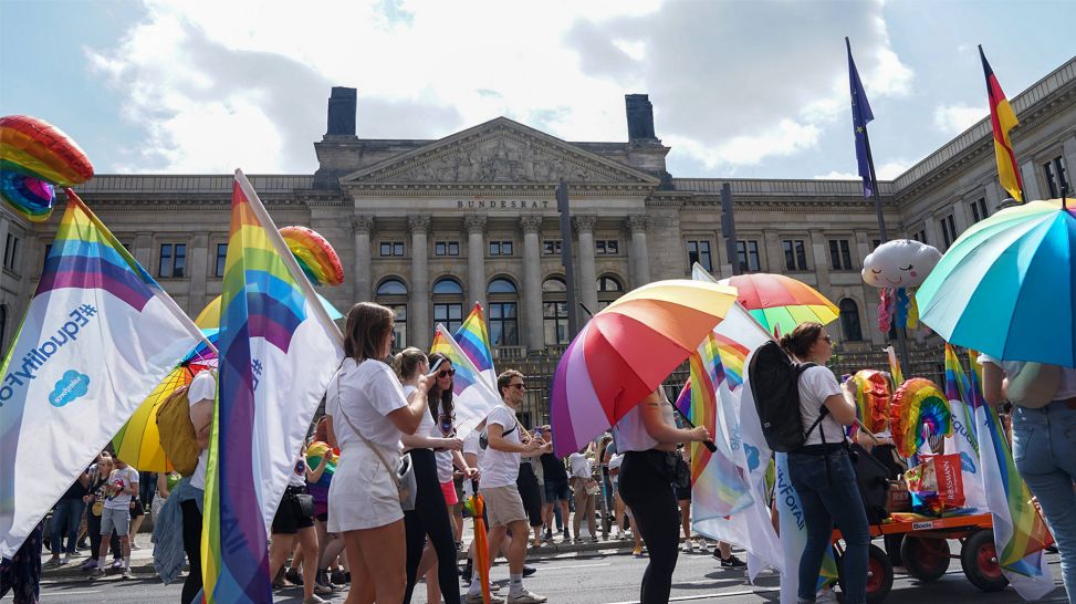 Menschen mit Regenbogenflaggen vor dem Bundesratsgebäude Berlin beim CSD 2021 (Bild: IMAGO / Fotostand)