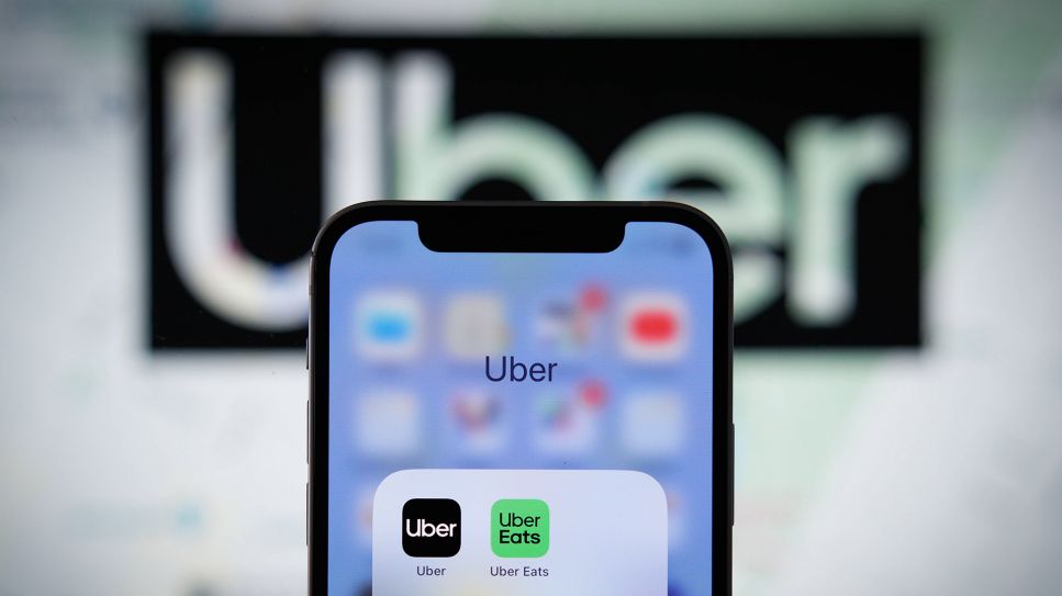 Smartphone mit Uber-App vor Uber-Logo (Bild: IMAGO / NurPhoto)