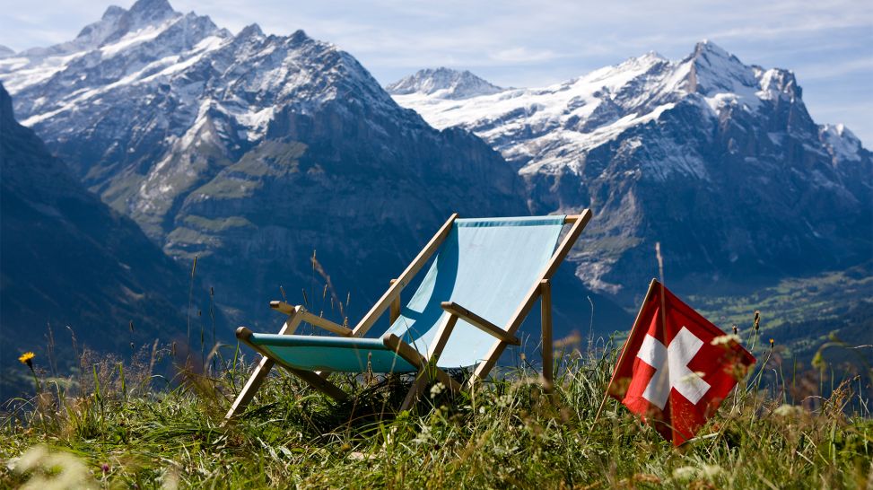 Schweizer Fahne und Liegestuhl vor Alpenpanorama (Bild: Colourbox)