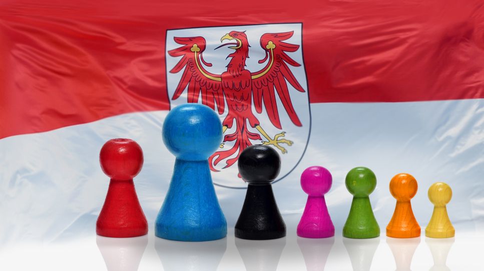 Montage: Spielfiguren in Farben der Parteien vor Brandenburgflagge (Quelle: rbb/picture alliance/ZB|Ralf Hirschberger/CHROMORANGE|Christian Ohde)
