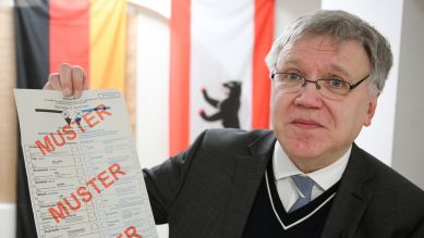 Stephan Bröchler, Landeswahlleiter für Berlin, zeigt am 09.01.2024 einen Stimmzettel zum Beginn der Briefwahl (Bild: picture alliance/dpa | Jens Kalaene)