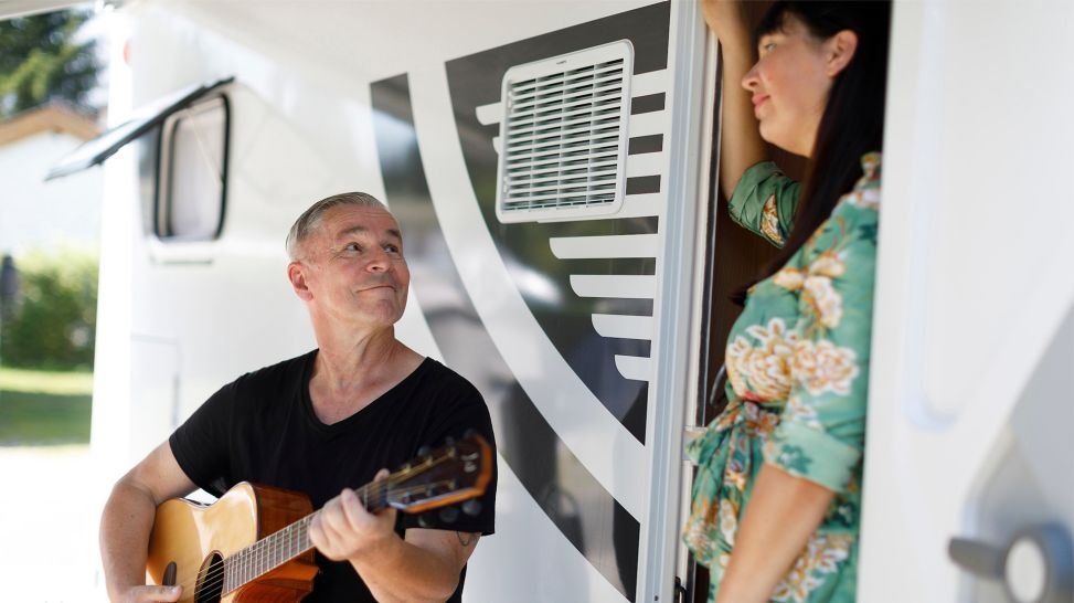 Jörg mit Gitarre vor Nicole, die im Eingang ihres Wohnmobiles steht (Bild: MDR/timeline/Alex Kraus)