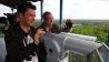 Sascha Hingst mit Radführer und Kameramann auf einer Aussichtsplattform (Quelle: Elia Brose)