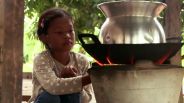 Ein kleines Mädchen sitzt vor einer Feuerstelle und kocht (Quelle: rbb/KIKA)