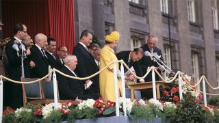 Die britische Queen Elizabeth II. (M, in Gelb) gemeinsam mit Bundeskanzler Ludwig Erhard (sitzend, l), Willy Brandt (l, neben der Queen), Regierender Bürgermeister von Berlin, und Prinz Philip (r, neben der Queen) während eines Staatsbesuchs im Mai 1965 auf einer Ehrentribüne vor dem Schöneberger Rathaus in Berlin., Quelle: dpa