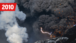 Ein Blitz zuckt in der Aschewolke des Eyjafjallajökull, der gerade Magma ausspeit, vorne der Lavastrom im Gletscher, der eine Wasserdampfwolke produziert, Eyjafjallajökull, Island,