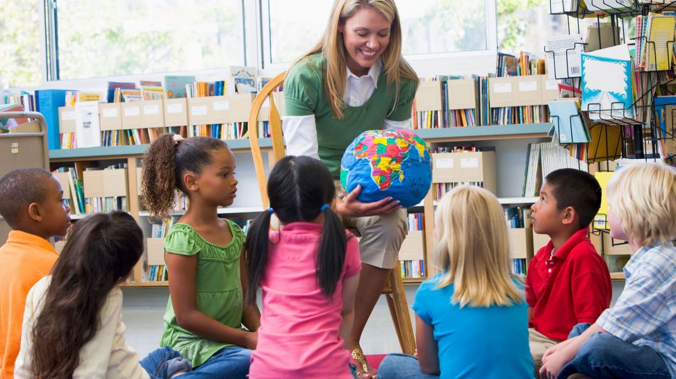 Kindergarten teacher and children looking at globe in library (Quelle: Colourbox)