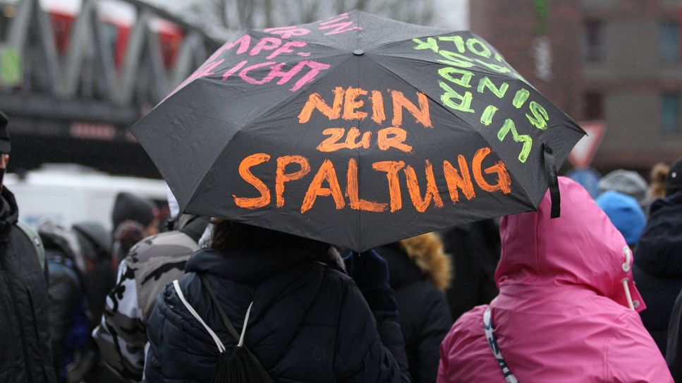 Regenschirm mit Aufschrift "Nein zur Spaltung" (Quelle: IMAGO / Hanno Bode)