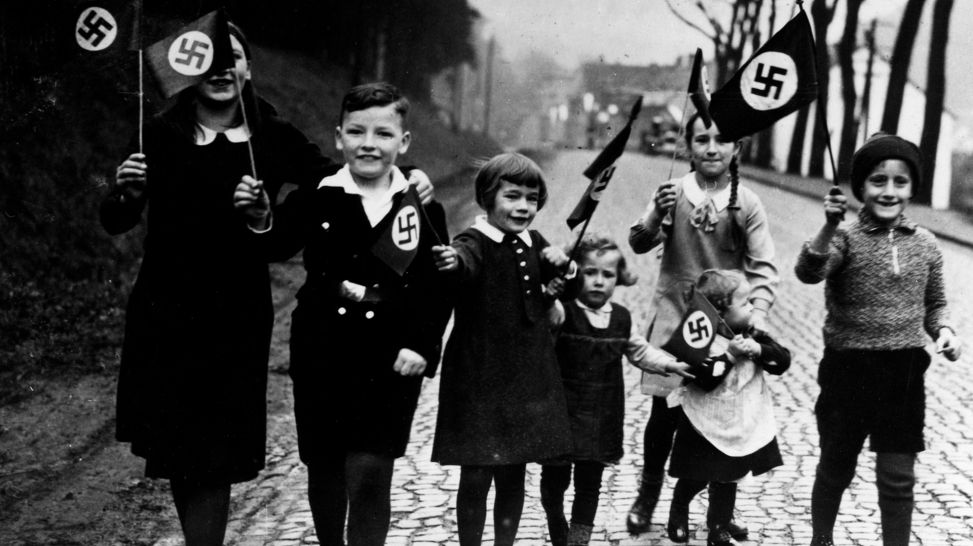Kinder gehen mit Hakenkreuzfahnen in der Hand spazieren. Propagandafoto für die Presse (Bild: rbb/Scherl/Süddeutsche Zeitung)