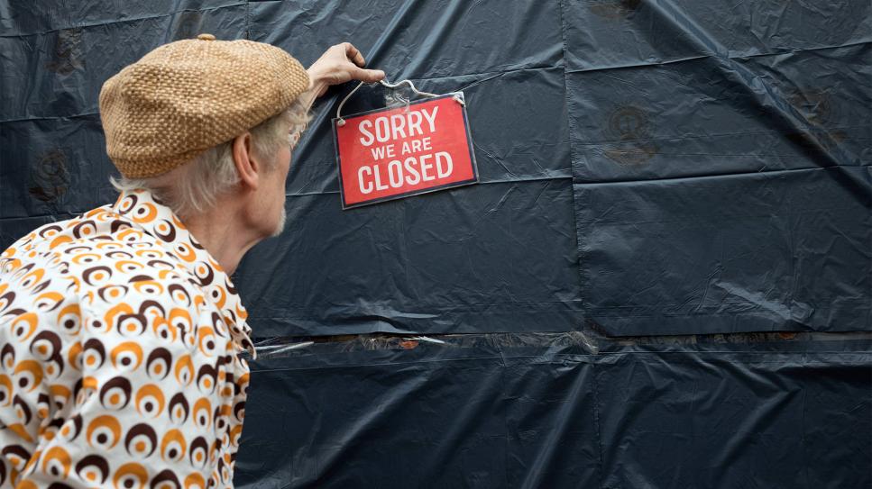 Ein Händler bringt ein Schild "Sorry we are Closed" an seinem Laden an; Quelle: Christian Mang/imago stock&people