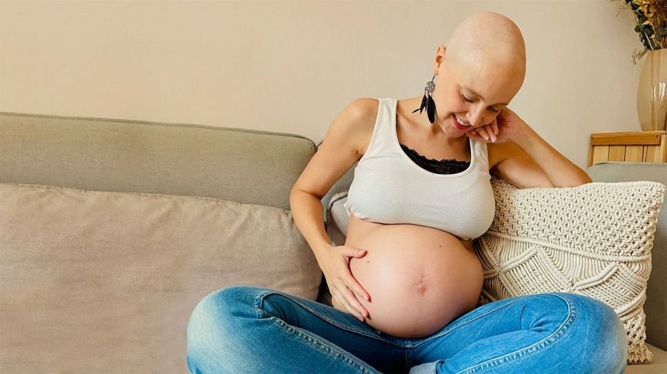 Katrin sitzt auf dem Sofa und streicht sich glücklich über ihren Schwangerschaftsbauch (Bild: rbb)