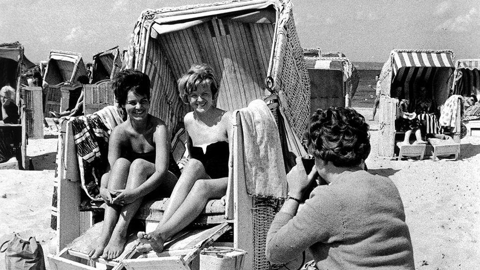 Junge Frauen in einem Strandkorb am Sandstrand von Binz auf Rügen werden für ein Erinnerungsfoto an ihren Urlaub im Juli 1961 (Bild: picture-alliance / dpa | ZB Burmeister)