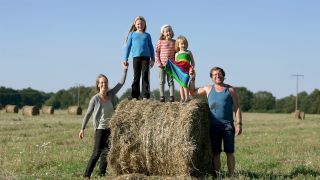Jana und Kai neben ihren drei Kindern, die auf einem Feld auf einem Stohballen stehen (Bild: rbb/Matthias Neumann)