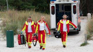 Nora Kaminski (Tanja Wedhorn) und ihr Kollege Lars Hinrichs (Bo Hansen) sowie ein weiterer Sanitäter (Wolfgang Stadler) eilen zu einem Notfall am Strand. © ARD Degeto/Boris Laewen