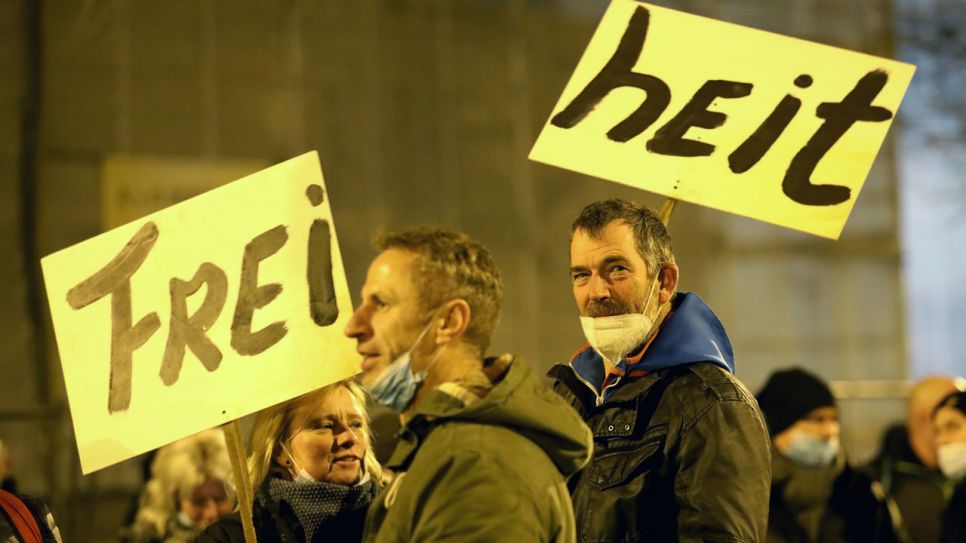 Demonstranten tragen ein zweigeteiltes Plakat mit der Aufschrift "Freiheit". Bild: ZB