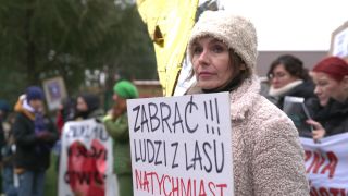 Frau mit einem Protestplakat (Aufschrift: "Lasst die Leute aus dem Wald raus- Sofort")