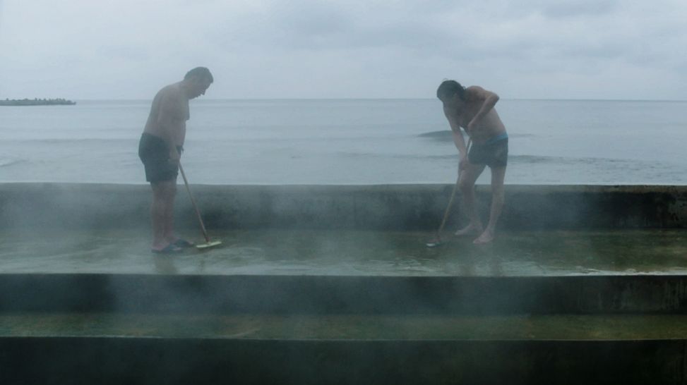 Zwei Männer in Badehose reinigen den Boden (Quelle: Filmuniversität Babelsberg)