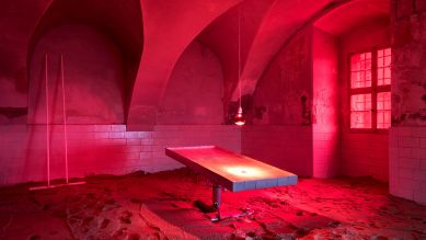 Rot beeuchteter Raum mit Keramik, Operationstischfuß, Wärmelampe und Elektrokabel(Bild: rbb/Jan Brockhaus)