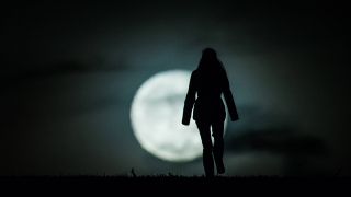 Die Silhouette einer Frau zeichnet sich vor dem aufgehenden Mond ab (Quelle: imago/Florian Gaertner/photothek.net)