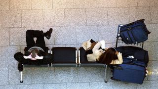 Paar wartet auf einer Bank am Flughafen (Quelle: imago/Thorge Huter)