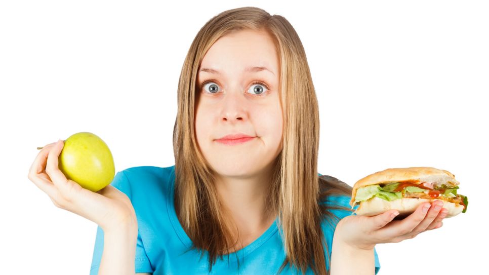 Frau wägt Obst gegen Fastfood ab (Quelle: Colourbox)