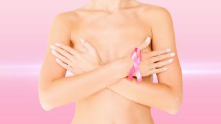 Frau verschränkt Hände vor der Brust und trägt Brustkrebsschleife (Quelle: Colourbox)