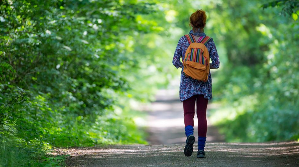 Frau läuft in langer Kleidung durch Wald (Quelle: imago/Photocase)