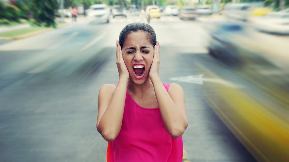 Frau steht in einer Stadt auf der Straße und hält schreiend Ohren zu (Bild: Colourbox)