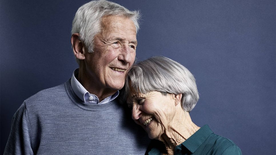 Seniorenpaar liegt sich lächelnd im Arm (Bild: imago/Westend61)