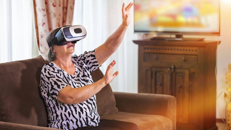 Ältere Frau auf Sofa mit VR-Brille (Bild: imago images/Panthermedia)