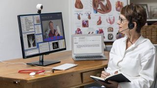 Ärztin in einer Praxis, kommuniziert mit dem Patienten über eine Webcam (Quelle: imago / Jochen Tack)