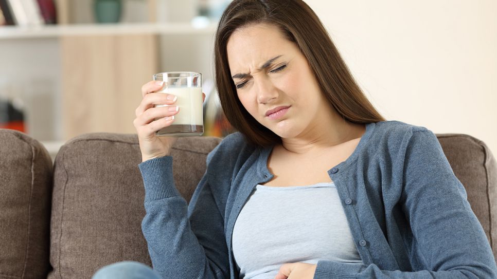 Frau mit Glas Milch in der Hand greift sich an schmerzenden Bauch (Bild: Colourbox)