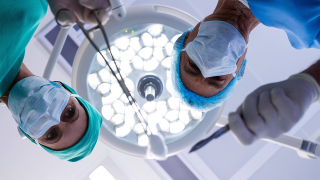 Blick von unten in Gesichter von Ärzten in einem OP (Bild: imago images/Panthermedia)
