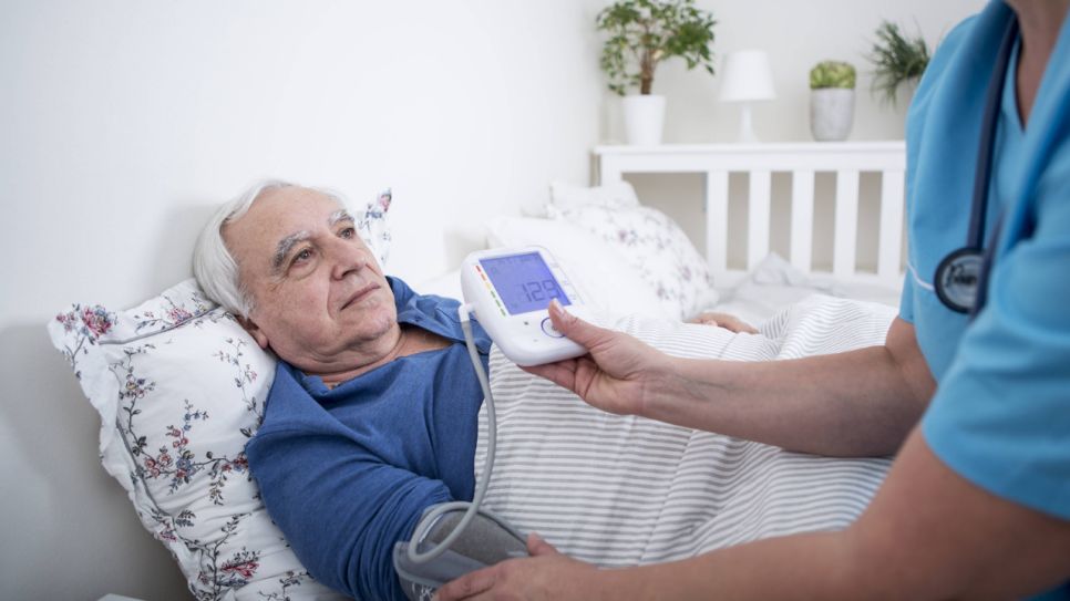 Ambulante Pflegekraft misst Blutdruck bei älterem Herren (Bild: imago images/Westend61)