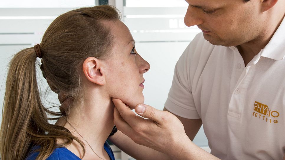Physiotherapeut untersucht Kiefermuskulatur einer Frau (Bild: imago images/Jochen Tack)