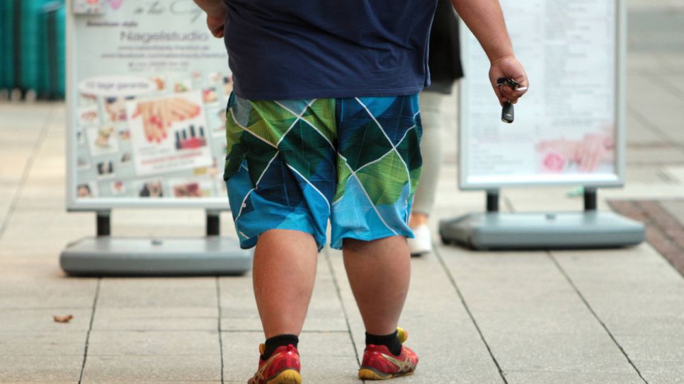 Stark übergewichtiger Mann spaziert in der Stadt (Quelle: imago/Ralph Peters)