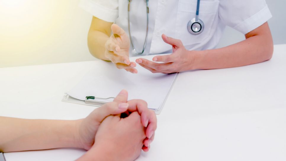 Hände von Ärztin und einem Patienten mit Schreibutenssilien auf Tisch (Bild: Colourbox)