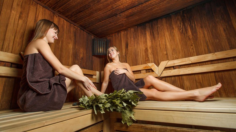 Zwei Frauen mit einem Birkenzweig in einer Sauna (Bild: imago images/Panthermedia)