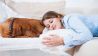 Frau und Hund schlafen auf Sofa (Bild: imago images/Westend61)