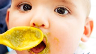 Baby maacht Mund für einen Löffel Brei auf (Bild: imago images/Westend61)