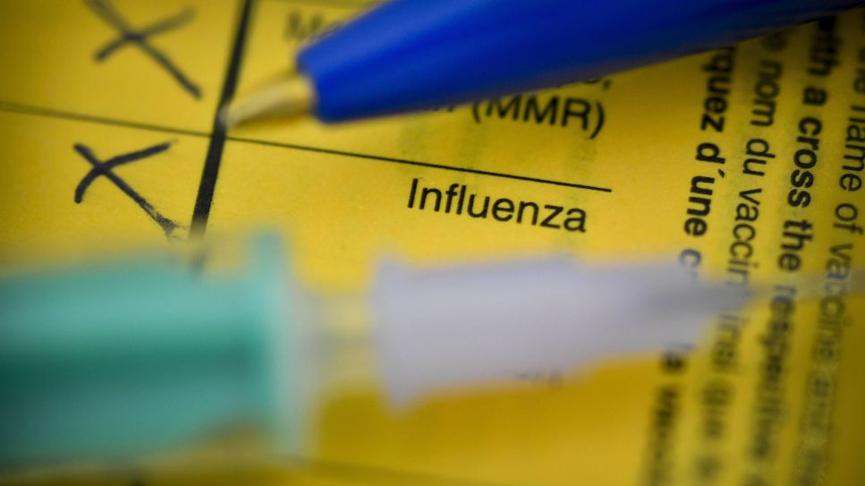 Impfpass mit Schrift Influenza unter Spritze und Stift (Bild: imago images/Schöning)
