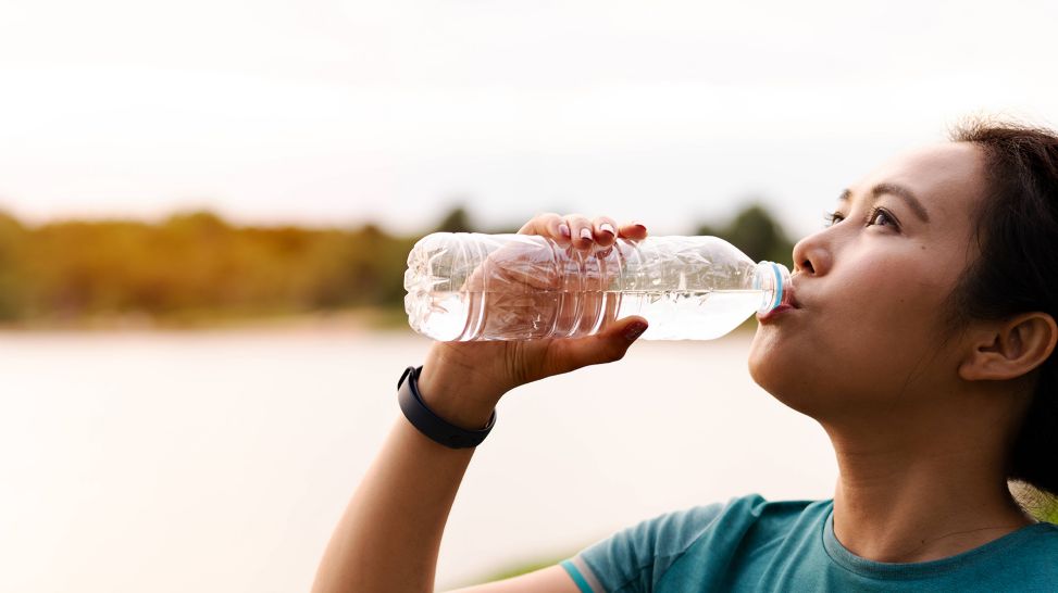 Junge Frau trinkt Wasser aus einer Flasche (Bild: imago images/Cavan Images)