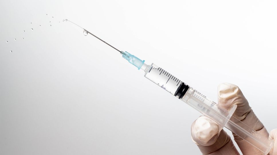 Behandschuhte Hand hält Impfspritze (Bild: imago images/MiS)