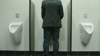 Mann uriniert in ein Pissoir (Quelle: colourbox)