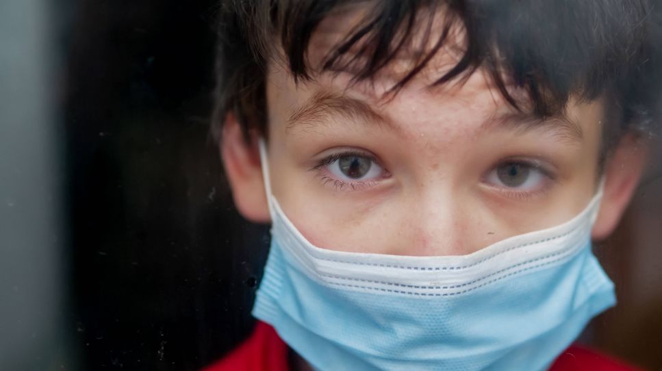 Kind mit medizinischer Maske schaut in Kamera (Bild: imago images/CHROMORANGE)