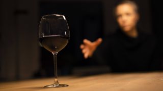 Frau im Hintergrund greift nach gefülltem Rotweinglas (Bild: imago images/photothek)