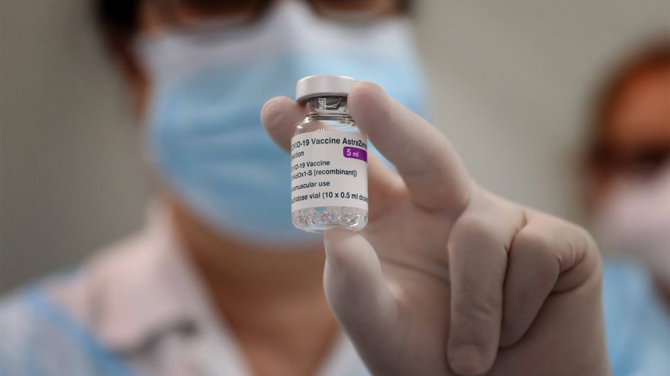 Hand hält Impfflasche AstraZeneca (Bild: imago images/ ZUMA Wire)