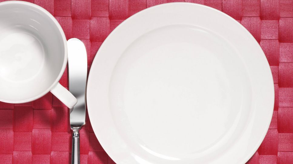 Gedeck, leerer weißer Teller und Tasse, Messer auf rotem Platzset (Quelle: image / imagebroker)