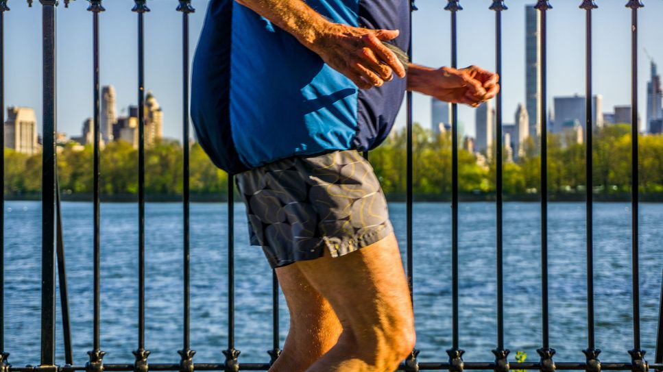 Älterer Herr in Shorts joggt auf Brücke vor Stadt (Bild: unsplash/Clay LeConey)