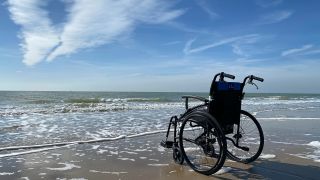 Leerer Rollstuhl an einem Strand (Bild: unsplash/Hans Moermann)